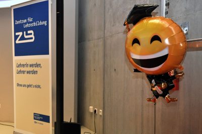 Ein Luftballon in Form eines lachenden Emojis mit Doktorhut
