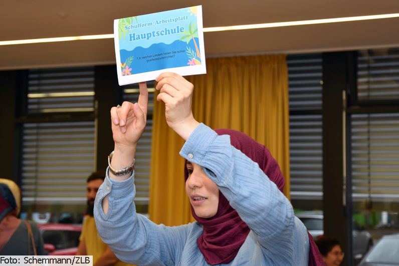 Teilnehmer*in des Sommerfestes 2022 von Lehrkräfte PLUS mit Infobroschüre in der Hand