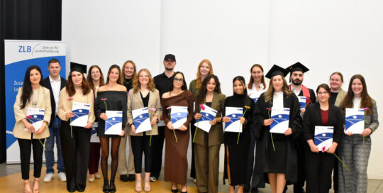 Eine Gruppe Absolvent*innen steht auf der Bühne.