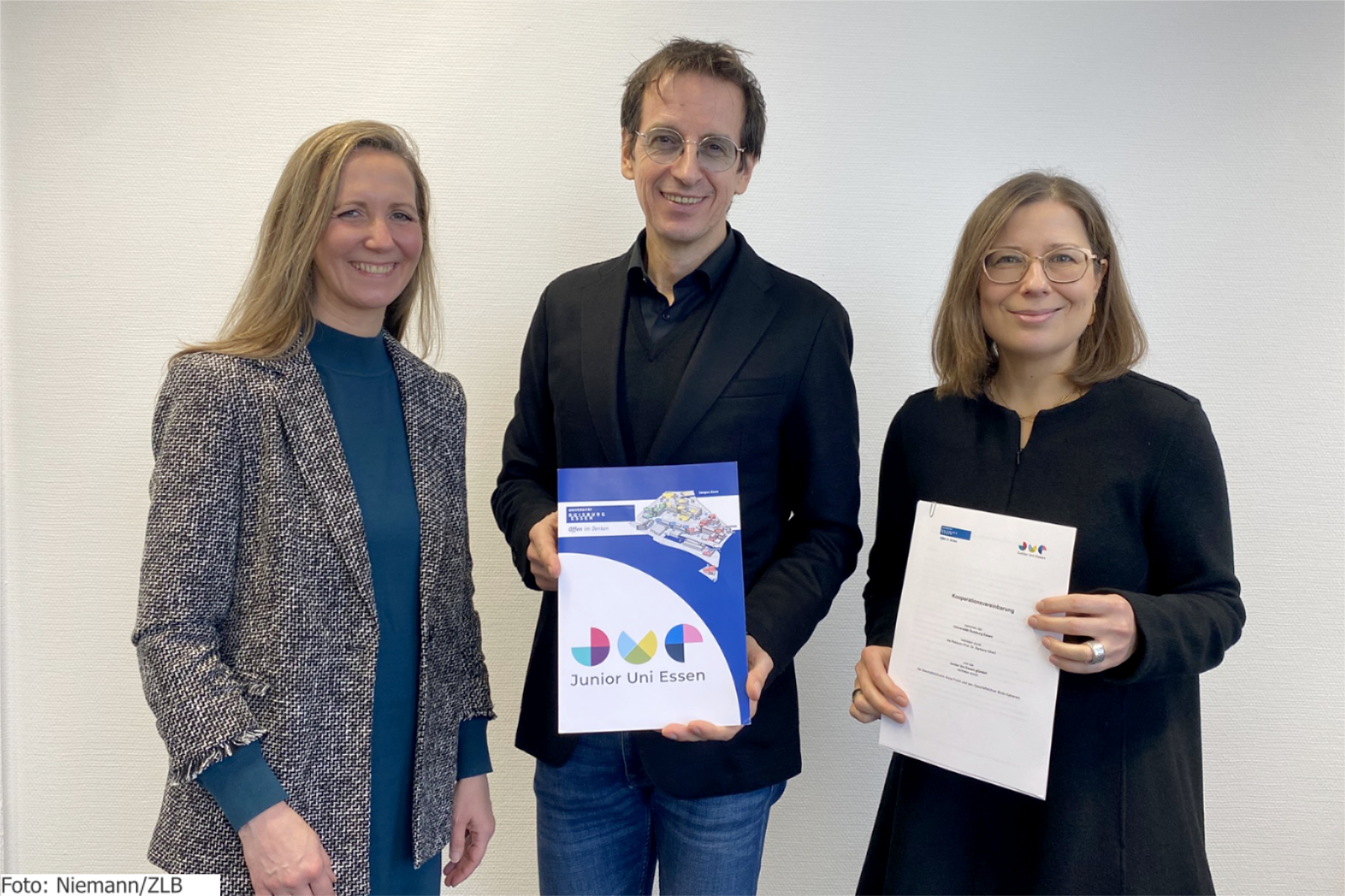 Zwei Frauen und ein Mann präsentieren einen Kooperationsvertrag