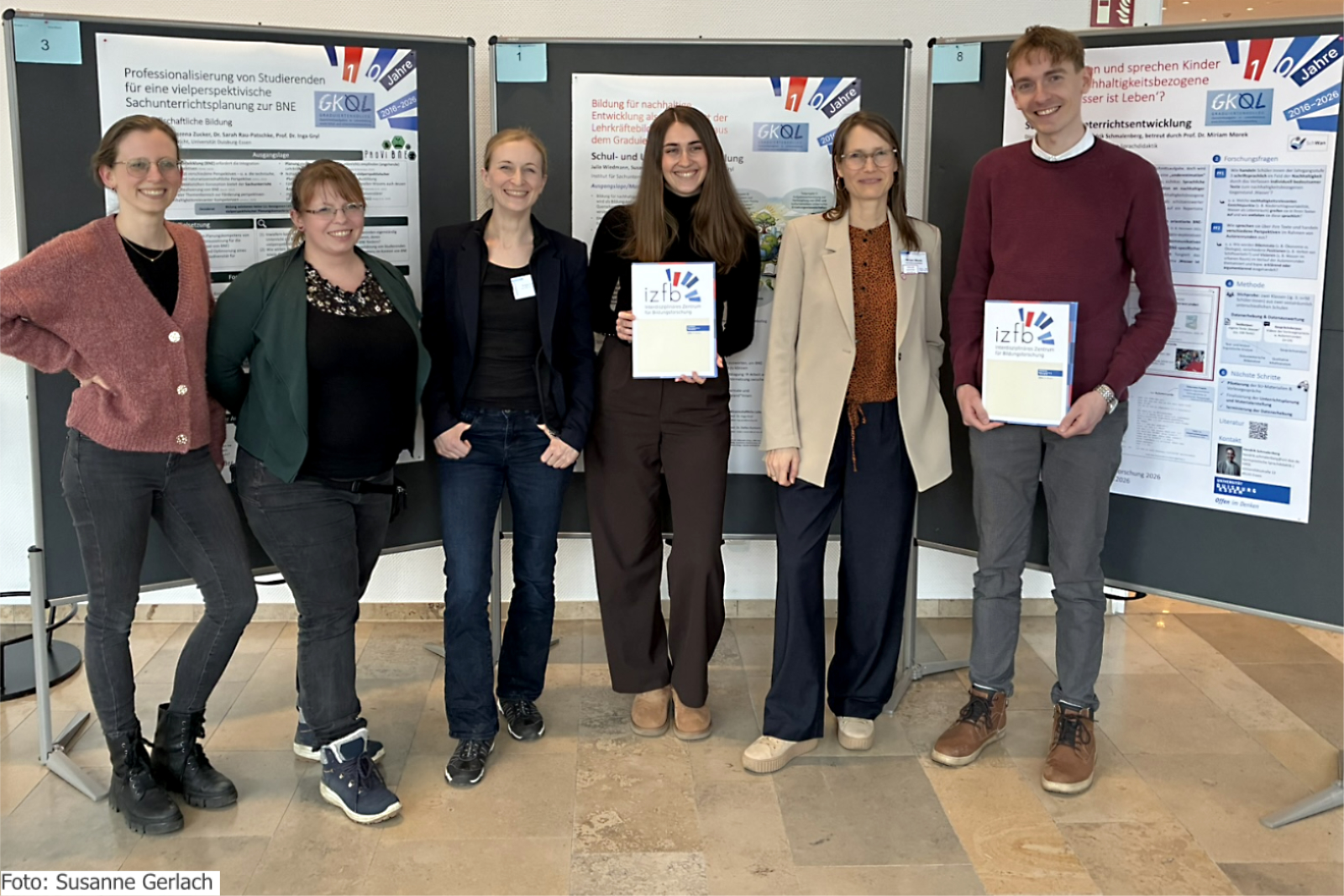 Preisträger*innen und Projektbeteiligte vor den GKQL-Postern